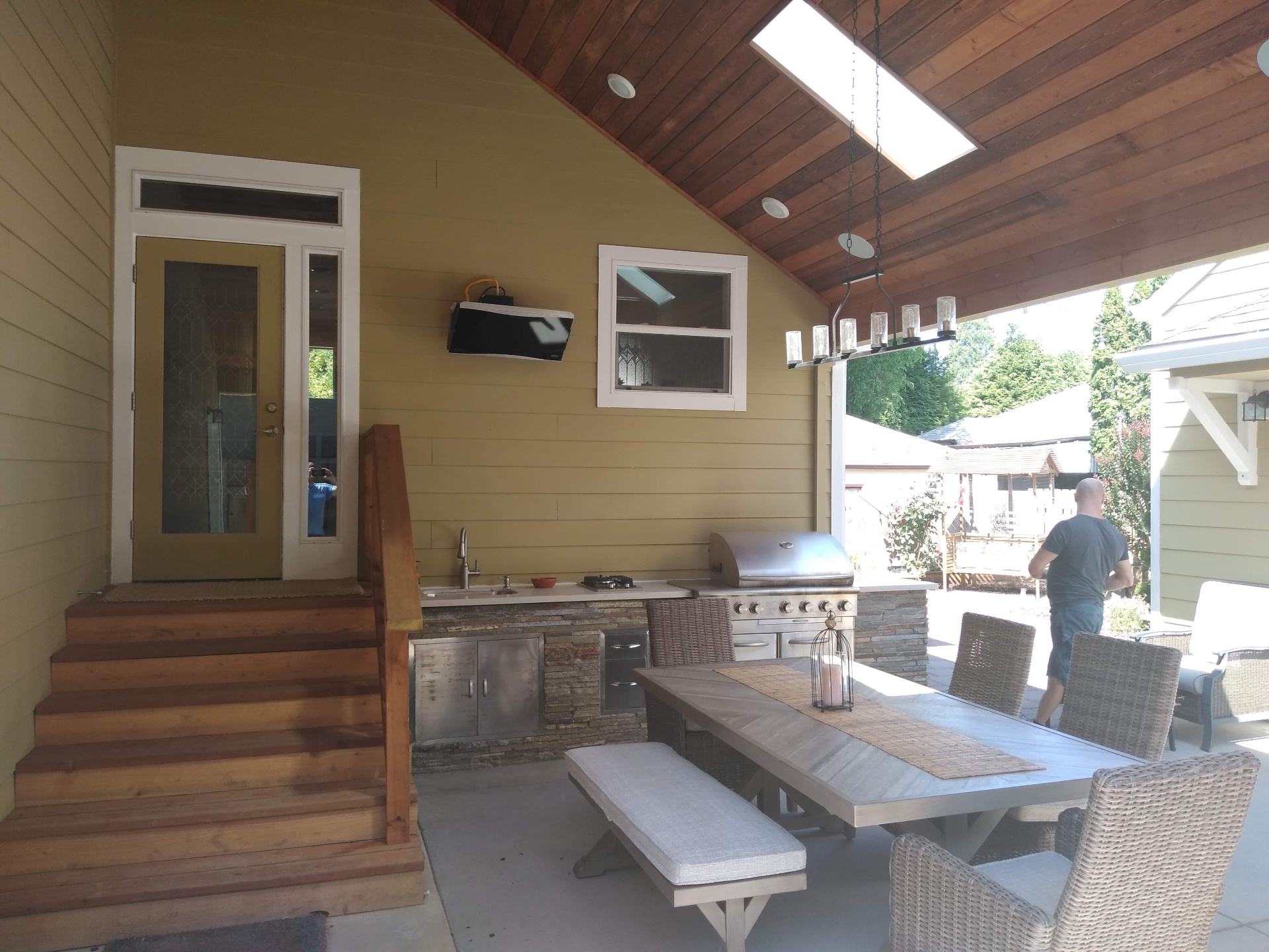 Covered outdoor kitchen with stone base and vaulted cedar ceiling